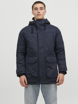 Navy blue padded jacket with a high collar, drawstring hood, and two front pockets. Features a smooth texture and button closures on sleeves.
