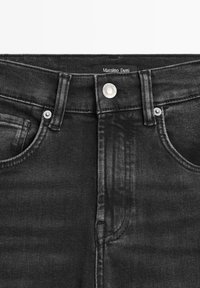 Jeans en denim noir à taille mi-haute, dotés d'une fermeture à bouton et zip, de poches avant, et d'une étiquette portant la mention "Massimo Dutti" près de la ceinture.