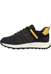 Zapatos deportivos negros con acentos amarillos, paneles texturizados y cordones negros. Presentan una entresuela blanca acolchada y una suela de goma para mayor tracción.