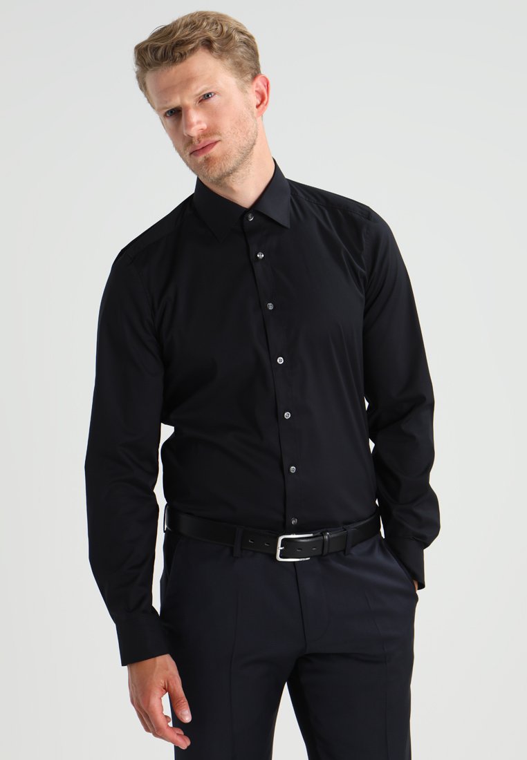 Chemise noire à manches longues et à boutonnière avec un design ajusté, texture lisse et léger éclat. Présente un col classique et des boutons assortis.