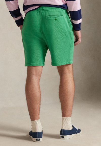 Πράσινα βαμβακερά σορτς με ελαστική μέση, πλαϊνές τσέπες και μια πίσω τσέπη. Συνδυασμένα με ναυτικά παπούτσια και λευκές κάλτσες με ρίγες.