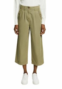 Olive green wide-leg trousers with front pockets, button closure, and a crease down the front, paired with white sneakers.