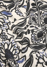 Stoff mit Blumenmuster in Schwarz, Blau und Creme. Zeigt große Blumen und filigrane Blattmuster, hergestellt aus weichem Textilmaterial.