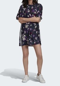 Šaty s květinovým potiskem v tmavých tónech s krátkými rukávy, s bílými vertikálními pruhy na bocích a volným střihem. Vyrobeno z lehkého materiálu.