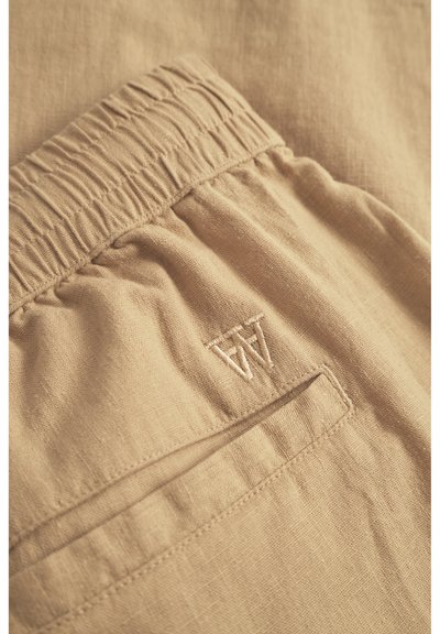 Beige Leinen-Shorts mit gerafftem Bund, versehen mit einem kleinen gestickten Logo und einer Gesäßtasche. Der Stoff hat eine weiche, strukturierte Optik.