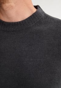 Pull en tricot côtelé gris foncé avec un col rond, présentant un tissu texturé et de subtils détails de couture.