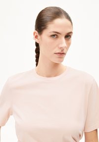 Lichtroze T-shirt, korte mouwen, ronde halslijn, zachte textuur, minimalistisch ontwerp zonder logo's of opvallende details.