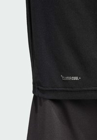 Tejido atlético negro con textura suave; presenta una etiqueta ClimaCool+. El diseño ofrece un estilo ajustado y transpirable, adecuado para prendas de rendimiento.