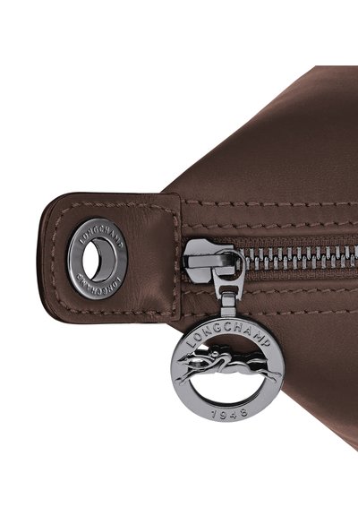 Brown leather bag zipper with silver Longchamp logo pull tab featuring a horse and rider and a metal button engraved with "Longchamp."