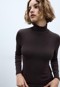 Brązowa bluzka z długim rękawem i golfem, wykonana z miękkiego, gładkiego materiału, z dopasowanym krojem i minimalnym detalem szwów.