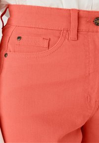 Koraalroze denim broek met een getailleerde taille, voork pocket en een gestructureerd oppervlak. Met metalen knoop en stiksels als details. Gladde afwerking.