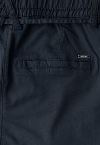 Marineblauwe stoffen shorts met een elastische tailleband, voorzien van een achterzak met een horizontale opening en een klein zilveren merkje.