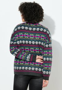 Strickpullover mit mehrfarbigen Schädel- und Blumenmustern auf schwarzem Hintergrund, mit Rundhalsausschnitt und langen Ärmeln.