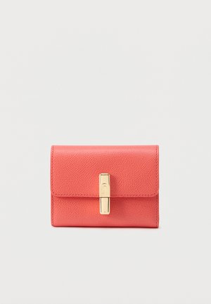 Cartera compacta de cuero coral con superficie texturizada y cierre rectangular dorado sobre un fondo claro y liso.