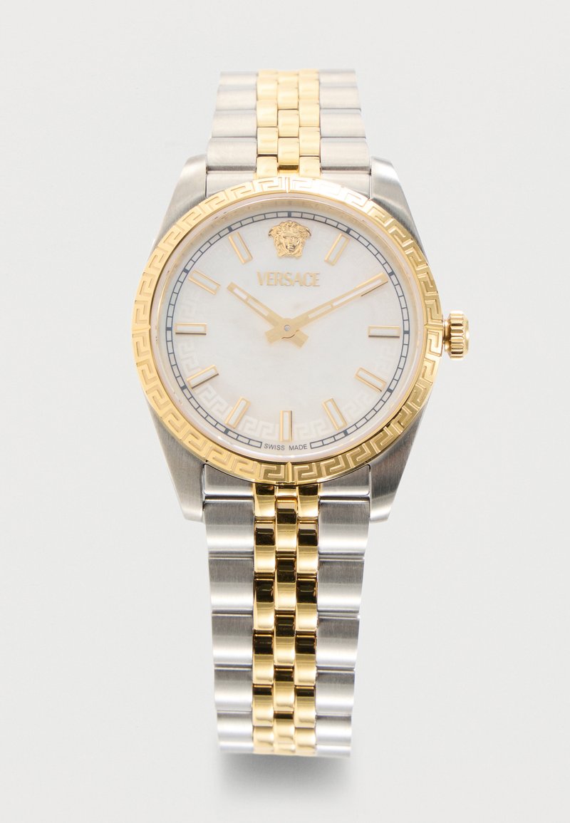 Ρολόι χειρός Versace με χρυστό και ασημί μεταλλικό λουράκι, λευκό καντράν, χρυσά σημάδια, λογότυπο Μέδουσας και χρυσή στεφάνη με ελληνικό κλειδί.