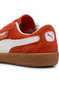 Punase nahkkingad valgete nahkdetailide, kummitaldade ja Puma logo detailiga kontsas. Madal disain, tekstureeritud viimistlus.