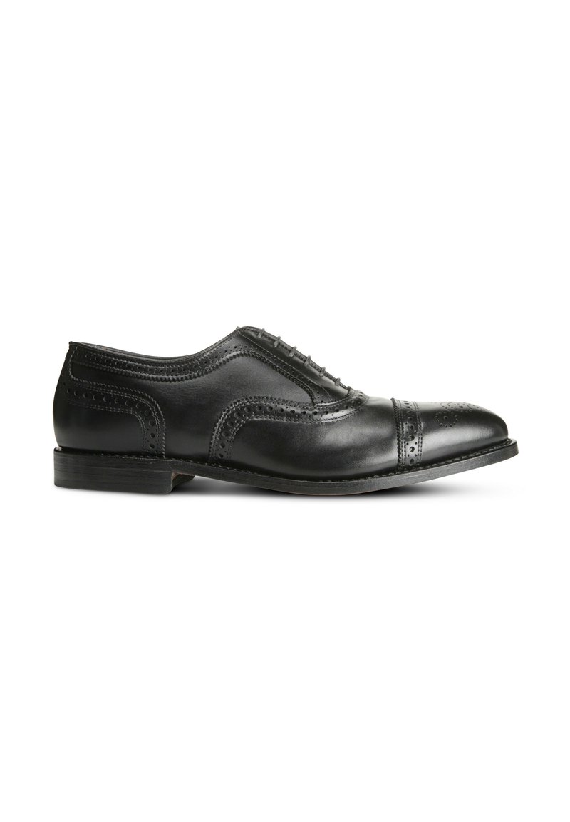 Chaussure Oxford en cuir noir avec une finition lisse, design à bout renforcé, détails décoratifs en brogue et un talon bas empilé.
