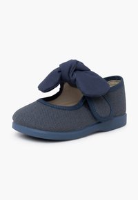 Chaussure en tissu bleu marine avec une finition texturée, bout arrondi et un nœud accentué à l'avant. Comprend une semelle rembourrée et une sangle ajustable.