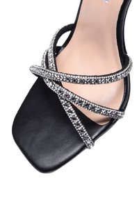 Scarpa nera con tacco alto e punta quadrata, decorata con molteplici cinturini abbelliti da cristalli sulla parte anteriore per un tocco di dettaglio in più.