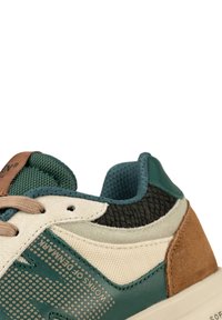 Multicolored sneaker featuring a mix of textured materials: green, beige, brown, and black accents. Light tan laces and mesh details.