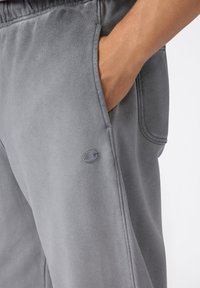 Grijze joggingbroek van zachte stof, met een elastische tailleband, zijzakken en een klein logo geborduurd op de linker dij.