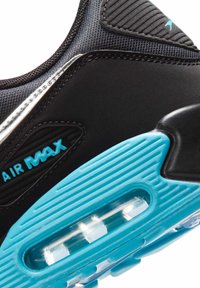 Close-up af en sort og blå Nike Air Max sneaker, der viser hælens luftpolstring og tekstureret såldesign.