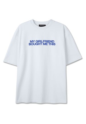 Hvit T-skjorte med korte ermer og blå tekst midt på brystet som lyder «MIN JENTE KJØPTE DENNE TIL MEG» i fete store bokstaver.