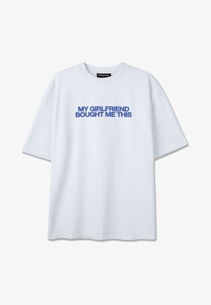 Valge lühikeste varrukatega T-särk, mille keskosas rinnal on sinise tekstiga kirjas suurtähtedega paksus kirjas "MINU TÜDRUKSÕBER OSTIS MIND SELLE".