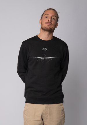 Black sweatshirt with a crew neck, featuring a white graphic illustration of a figure under an umbrella and stars. Soft texture, regular fit.