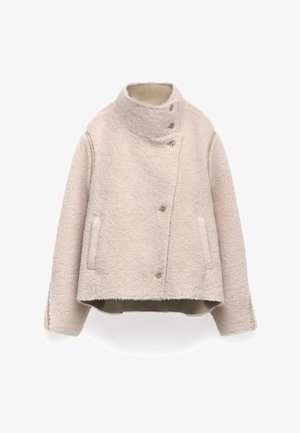 Giacca in sherpa fleece beige con colletto alto, chiusura a bottoni asimmetrica, due tasche frontali e maniche lunghe.