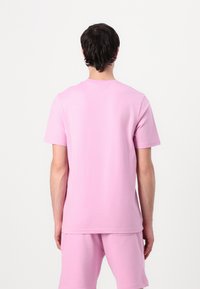 Rosa bomullströja med korta ärmar, rund halsringning och avslappnad passform, tillsammans med matchande shorts, slät textur och inga synliga mönster.