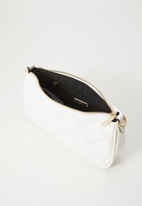 Valkoinen nahkainen clutch-laukku, jossa on rei'itetty geometrinen kuvio, kultaiset vetoketjukiinnitykset ja musta sisävuori. Kompakti ja virtaviivainen muotoilu.