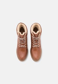 Botas de cuero marrón con forro de felpa beige, punta redonda y cordones blancos. Presentan una parte superior texturizada y un detalle de costura en contraste.