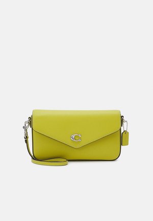 Limonkowo-zielona skórzana torebka na nadgarstek z srebrnym zapięciem w kształcie litery "C" oraz dopasowaną skórzaną zawieszką na srebrnym łańcuszku na jednolitym tle.