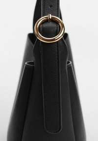 Sac en cuir noir avec une forme structurée. Doté d'une lanière verticale avec un accent en métal doré de forme circulaire pour la fermeture. Texture lisse.