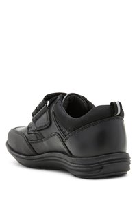 Sneaker noir avec une tige en cuir lisse et en tissu texturé, sangle ajustable, col rembourré et semelle en caoutchouc durable.