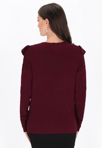 Bordowy sweter w prążki z akcentami na ramionach, długimi rękawami i okrągłym dekoltem. Teksturowana dzianina z luźnym krojem.