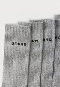 Šedé žebrované ponožky s černým logem „UMBRO“, ukazující texturovanou tkaninu a strukturovaný tvar, vhodné pro běžné nošení.