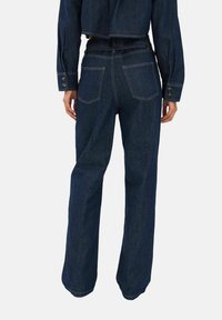Sötétkék farmer, széles szárú nadrág, két hátsó zsebbeli, látható varrás részletekkel és magas derékkal. Simára kidolgozott felület.