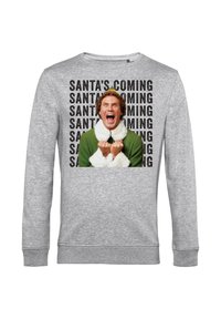 Šedá mikina s velkým grafickým motivem osoby oblečené v zeleném oblečení s bílými chlupatými akcenty a nápisem "SANTA PŘICHÁZÍ" v černé barvě.