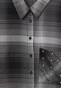 Camicia a quadre nera e grigia con colletto classico, bottoni neri e una tasca decorata con embellishments in argento.