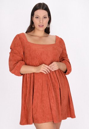 Rochie scurtă de culoare ruginită, din material moale, cu decolteu pătrat și fustă plisată, având o croială relaxată și o textură subtilă.