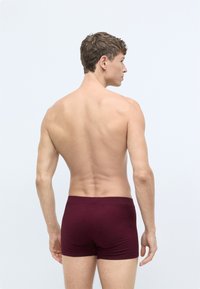 Bordeaux boxer shorts lavet af strækstof, med en sømløs talje, slim fit og glat tekstur, båret af en model set fra ryggen.