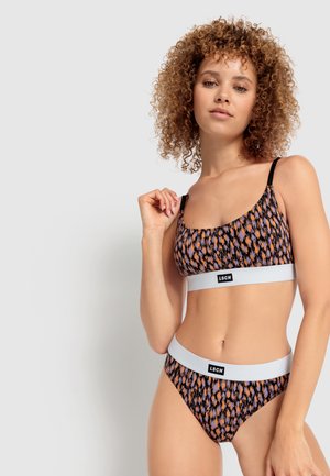 Svart och orange mönstrad underklädesuppsättning med en scoop-nacke bralette och höga trosor, med grå elastiska band med en logotyp.