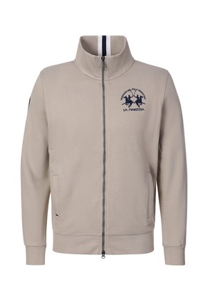 Veste beige zippée avec col montant, deux poches avant et logo brodé joueur de polo bleu marine sur la poitrine gauche.