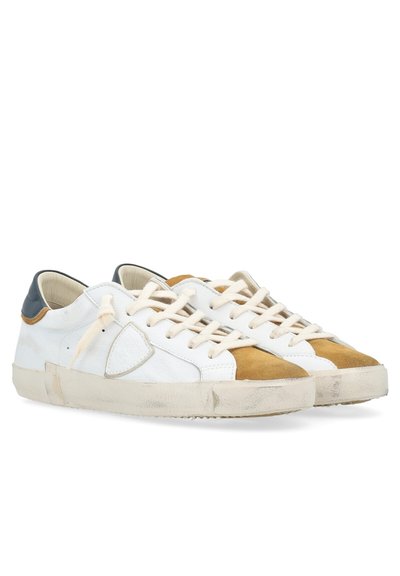 Baskets en cuir blanc avec un capuchon en suède marron, lacets crème et accent de talon gris ; finition texturée, apparence légèrement usée.