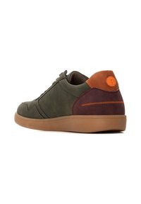 Zapatilla verde con detalles en marrón y burdeos. Cuenta con un upper texturizado, punta redonda y suela de goma. Cordones y logotipo en el talón.