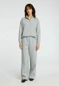 Light gray zip-up sweatshirt with a high collar and matching wide-leg pants, made from soft fabric, featuring a relaxed fit and elastic waistband.