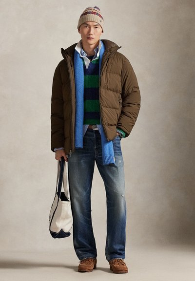 Brown puffer jacket, green and blue striped sweater, light blue shirt, blue scarf, distressed blue jeans, brown shoes, carrying a tote bag.