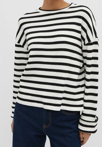 Pull en tricot rayé noir et blanc avec un col rond, des manches longues et une coupe décontractée ; le tissu présente une texture côtelée et une légère élasticité.